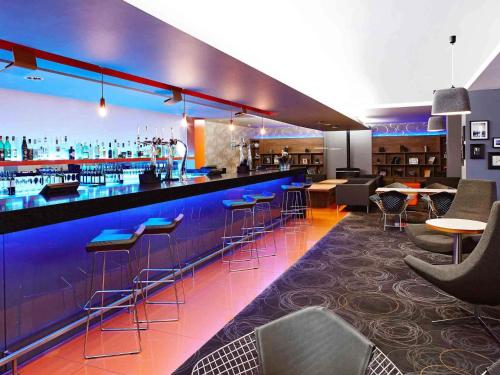 a bar with bar stools and tables in a restaurant at Novotel London Waterloo in London