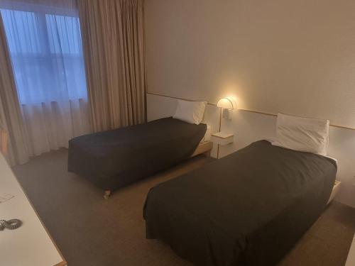 a hotel room with two beds and a window at Novotel Firenze Nord Aeroporto in Sesto Fiorentino
