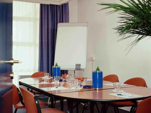a meeting room with a table with chairs and a board at Novotel Firenze Nord Aeroporto in Sesto Fiorentino
