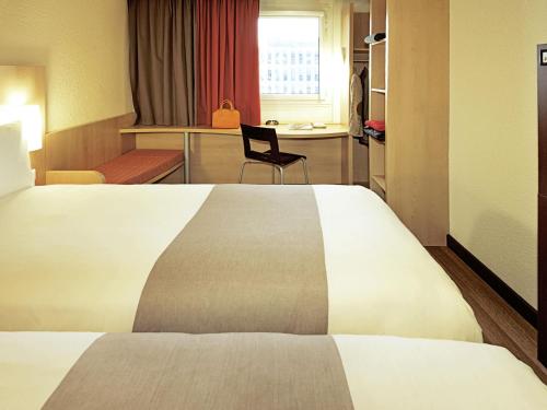 a hotel room with a large bed and a chair at Hotel ibis Braga in Braga