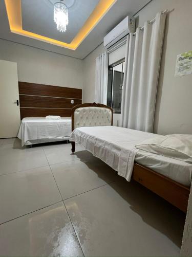 a bedroom with two beds and a window at Casa aconchegante 2min do centro in Primavera do Leste