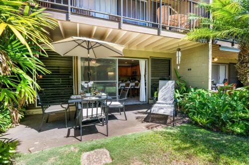 a patio with an umbrella and a table and chairs at Maui Sands 1B in Honokowai