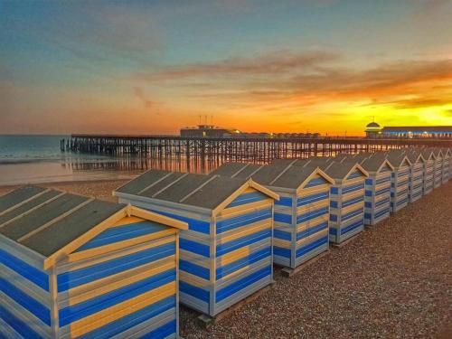 a row of beach huts on the beach with a pier at GENSING LODGE STUNNING SEASIDE MAISONETTE in St. Leonards