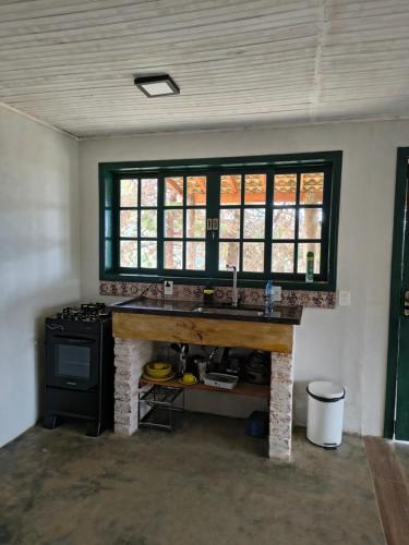 a kitchen with a counter with a stove and a window at Montanha Home in Monte Verde
