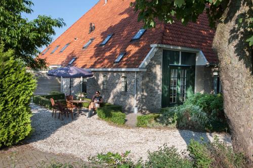 a person sitting in front of a house with an umbrella at Luxe vakantiehuis in Friesland in Joure