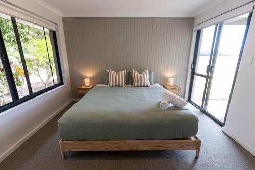 a bedroom with a large bed with two windows at Birak Cottage at Windance in Yallingup