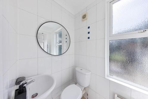 ein weißes Badezimmer mit Waschbecken und Spiegel in der Unterkunft Long Stay Ready King Bed Kitchen WiFi Town in Gravesend