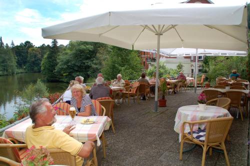 a group of people sitting at tables under an umbrella at Hotel Goldner Anker in Bad Elster