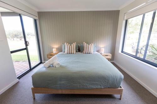 une chambre avec un grand lit avec deux fenêtres dans l'établissement Birak Cottage at Windance, à Yallingup