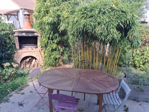 a wooden table and two chairs with a table and a fireplace at Chez Loti 2 in Louviers