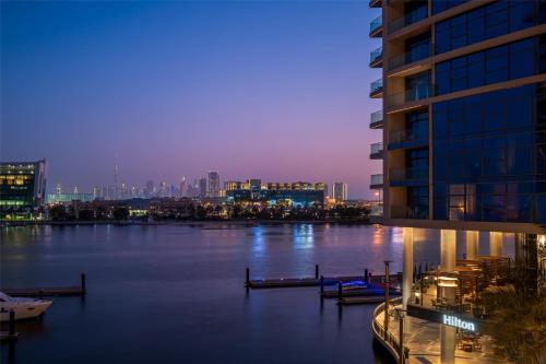 a view of a river with a city at night at Hilton Dubai Creek Hotel & Residences in Dubai