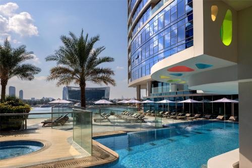 a hotel swimming pool with chairs and umbrellas at Hilton Dubai Creek Hotel & Residences in Dubai