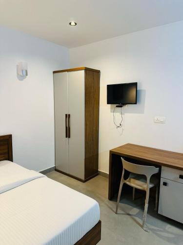 a bedroom with a bed and a desk with a television at ZAHIR RESIDENCY calicut in Kozhikode