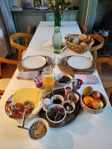 a table with plates of food and bowls of fruit at Chambre d'hote à Middelburg in Middelburg