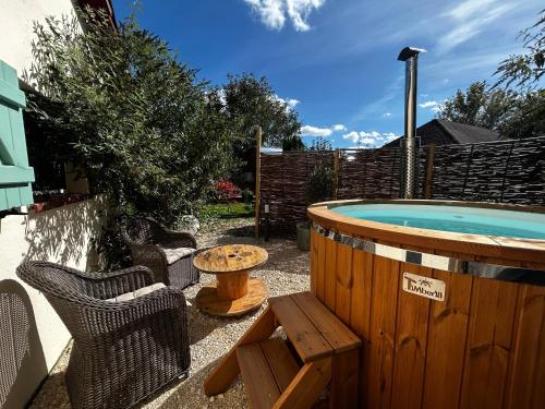 a backyard with a hot tub and a table and chairs at Domaine de la Mance - Maisonnette avec cheminée, bain nordique en supplément in Vitrey