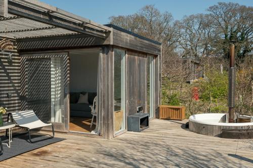 a glass house with a tub on a wooden deck at Fritton Lake Retreats in Fritton Norfolk