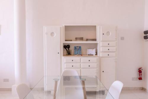 a dining room with a glass table and a dresser at Valletta Collection - Grand Harbour Suites 9A in Valletta