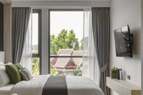 une chambre avec un lit et une grande fenêtre dans l'établissement The Ozone Lounge Lovers Golf View Bangtao, à Laguna Phuket