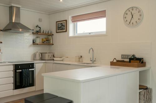 a white kitchen with a clock on the wall at Fritton Lake Retreats in Fritton Norfolk