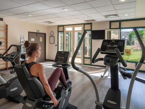 a woman riding on a treadmill in a gym at Mercure Bordeaux Chateau Chartrons in Bordeaux