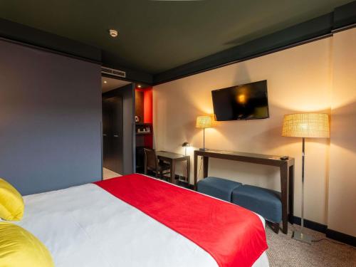 a hotel room with a bed and a flat screen tv at Mercure Bordeaux Chateau Chartrons in Bordeaux