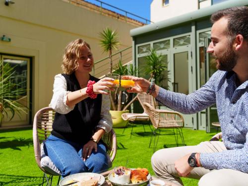 a man and a woman drinking a glass of orange juice at Mercure Bordeaux Chateau Chartrons in Bordeaux