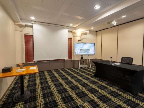a large room with a projection screen and a podium at Mercure Bordeaux Chateau Chartrons in Bordeaux