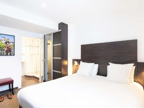 a bedroom with a large white bed and a chair at Mercure Strasbourg Centre Petite France in Strasbourg