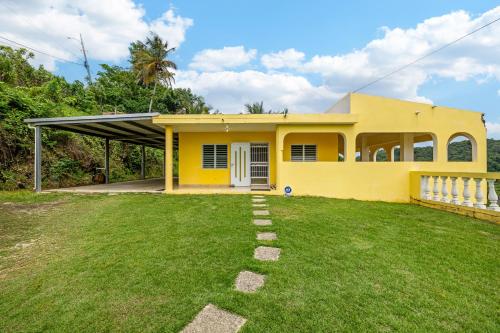 a yellow house with a lawn in front of it at Hilltop Getaway with Huge Terrace in Fajardo