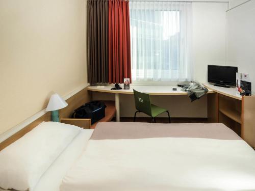 a hotel room with a bed and a desk with a computer at ibis Koblenz City in Koblenz