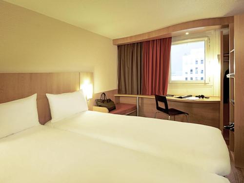 a hotel room with a large white bed and a desk at ibis Koblenz City in Koblenz
