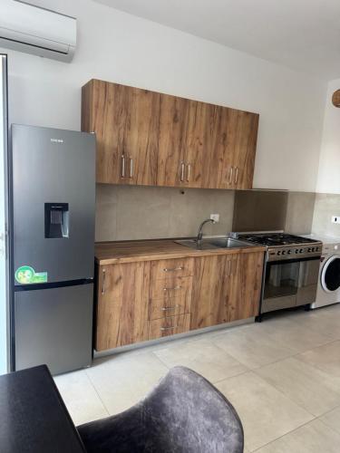 a kitchen with wooden cabinets and a stainless steel refrigerator at Velipoja Dream Villa in Velipojë