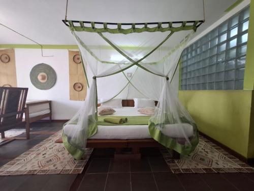 a bedroom with a bed with a mosquito net at Gassy Country House Ivato Airport in Ivato