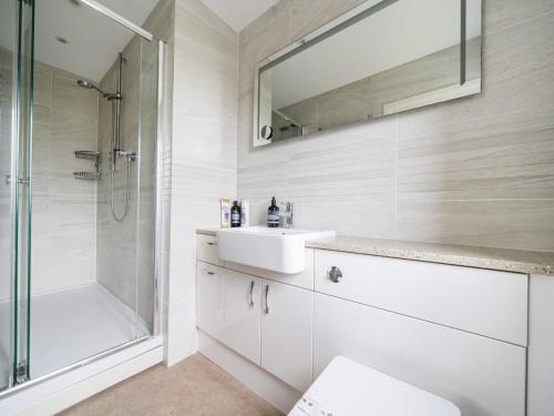 a white bathroom with a sink and a shower at Pass the Keys Spacious family home in Surrey in Addlestone