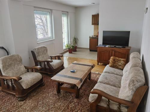 a living room with a couch and chairs and a tv at Apartman Urban Rest in Doboj