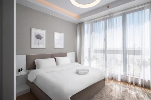 a bedroom with a white bed and a large window at AEON Towers Lucky Cloud #701 in Banī Ghālib