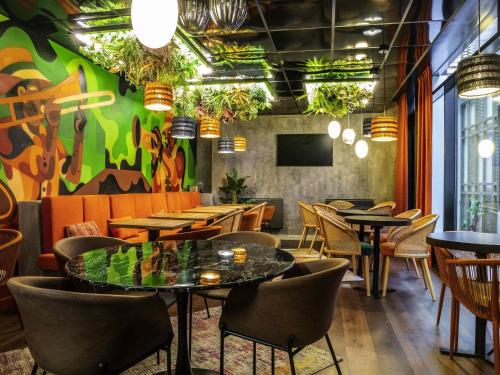 a restaurant with tables and chairs and a colorful wall at ibis Paris Place d’Italie 13ème in Paris