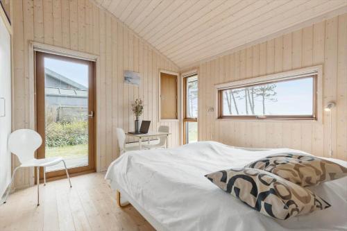 ein Schlafzimmer mit einem Bett, einem Fenster und einem Stuhl in der Unterkunft 8451 Knebel - Fyrrevej 9 in Knebel