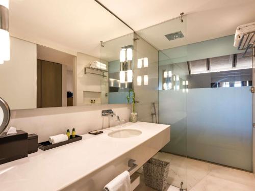 a bathroom with a sink and a glass shower at Sofitel Legend Santa Clara Cartagena in Cartagena de Indias