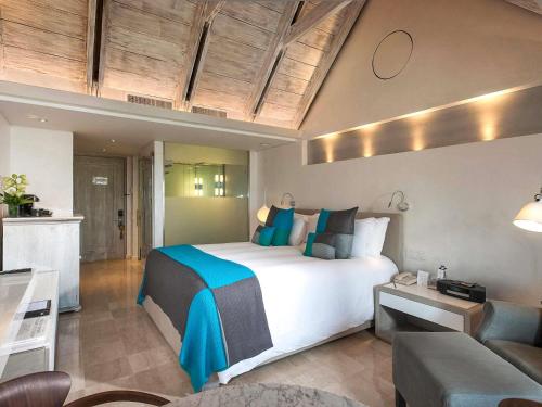 a bedroom with a large white bed and a couch at Sofitel Legend Santa Clara Cartagena in Cartagena de Indias