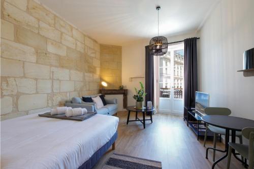 a bedroom with a large bed and a living room at Appartements - Bordeaux Centre Gare in Bordeaux