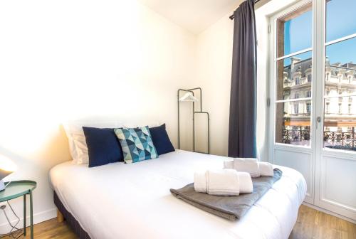 a white bed in a room with a window at Appartements - Bordeaux Centre Gare in Bordeaux