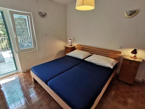 een slaapkamer met een blauw bed en een raam bij Apartments DeMori in Primošten