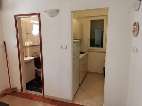 een witte keuken met een spiegel en een wastafel bij Apartments DeMori in Primošten