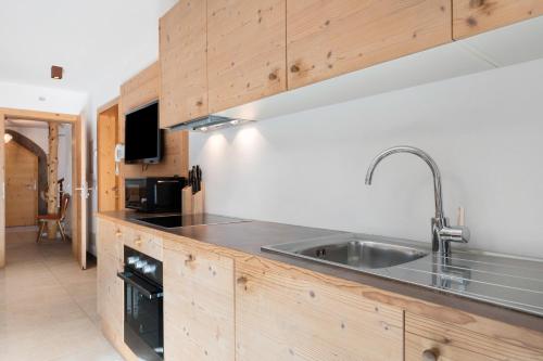 a kitchen with a stainless steel sink and wooden cabinets at Hotel Residence Olympia Sarntal in Sarntal