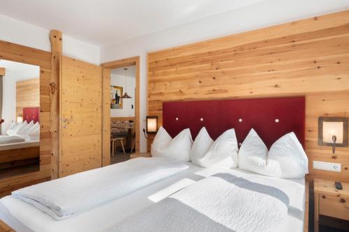 a bedroom with a large white bed with wooden walls at Hotel Residence Olympia Sarntal in Sarntal