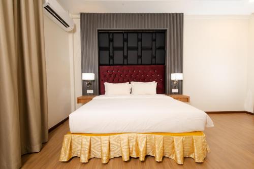 a bedroom with a large white bed with a red headboard at Hotel Pen Mutiara in Kampong Batu Maung