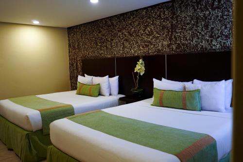 two beds in a hotel room with two beds at Hotel Colibrí Suites in Porlamar
