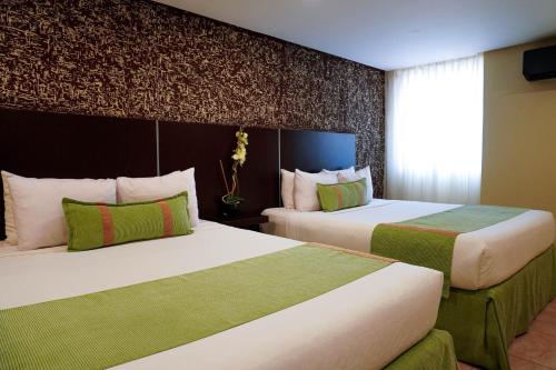 a hotel room with two beds and a window at Hotel Colibrí Suites in Porlamar