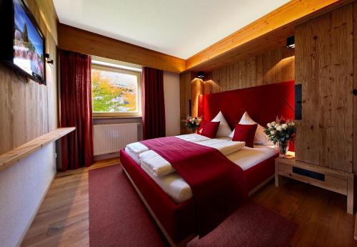 a bedroom with a large bed with a red headboard at Minglers Sportalm - Das Gourmet- und Genießerhotel in Kirchberg in Tirol